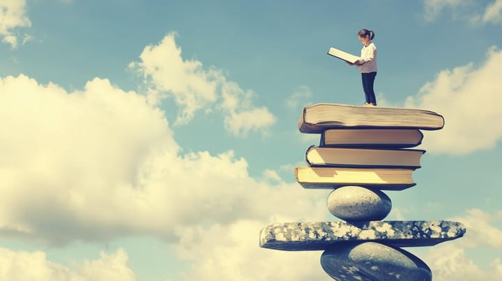 Image of a student standing on books balanced on stones