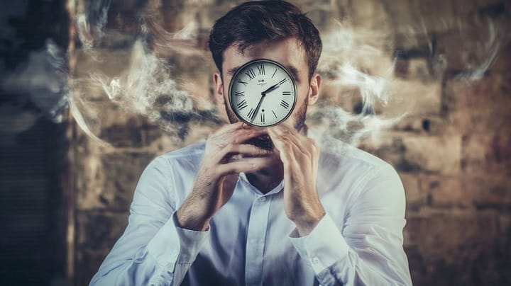 Image of a clock in front of a face with steam coming out of the ears